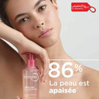 Woman holding a Bioderma product with text about skin soothing on a light background