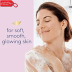 Woman with soap suds on her shoulders with text 'for soft, smooth, glowing skin' on a pink background.