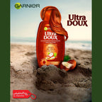 Garnier Ultra Doux shampoo bottle with coconut on a beach