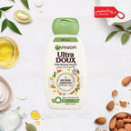 Garnier Ultra Doux shampoo bottle with almonds and almond milk on a white background