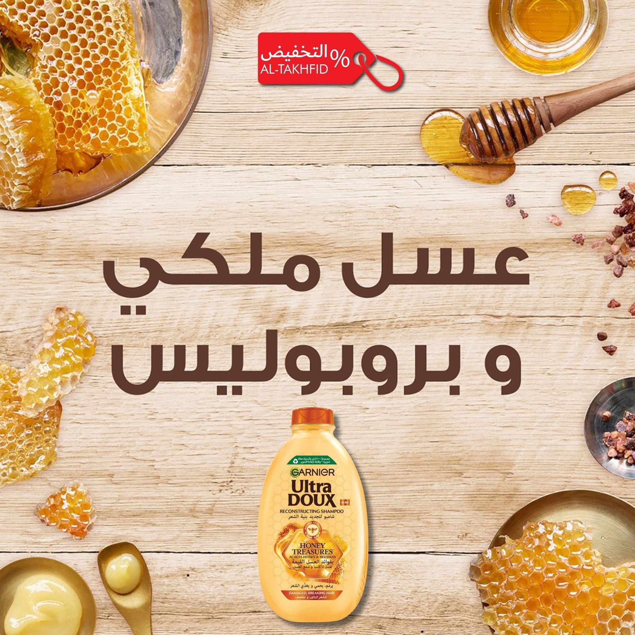 Garnier Ultra Doux honey bottle with honeycomb and honey on a wooden background