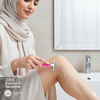 Woman shaving her leg with a Schick Exacta-2 Sensitive razor in a bathroom.