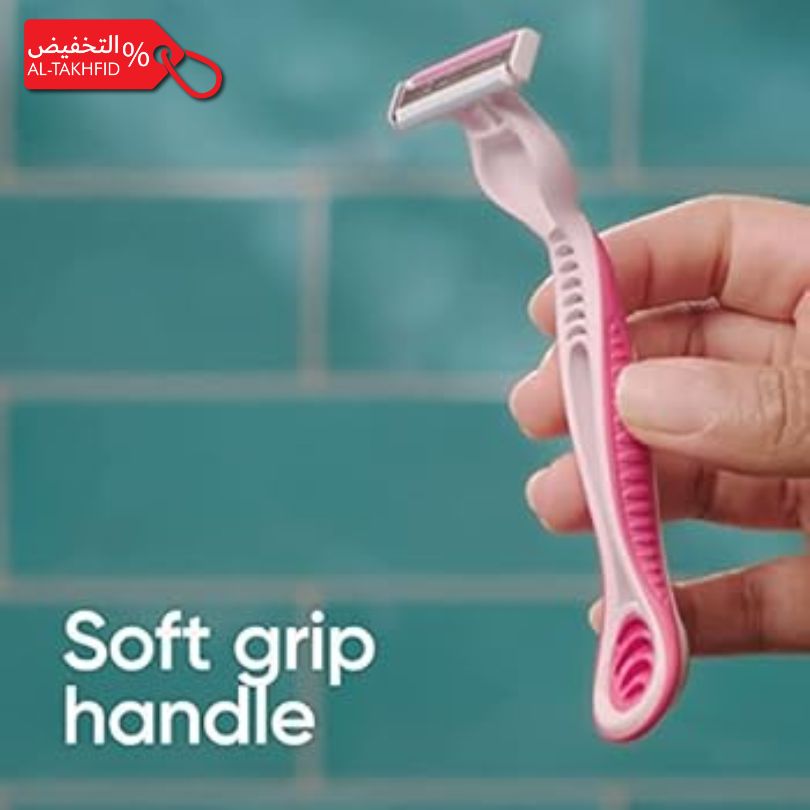Pink razor with soft grip handle held by a hand against a teal tiled wall.