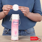 Person holding a Johnson's cotton pad with a pink bottle in the background
