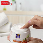 Person applying cream from a jar labeled 'Nourishing Gold' with a blurred background