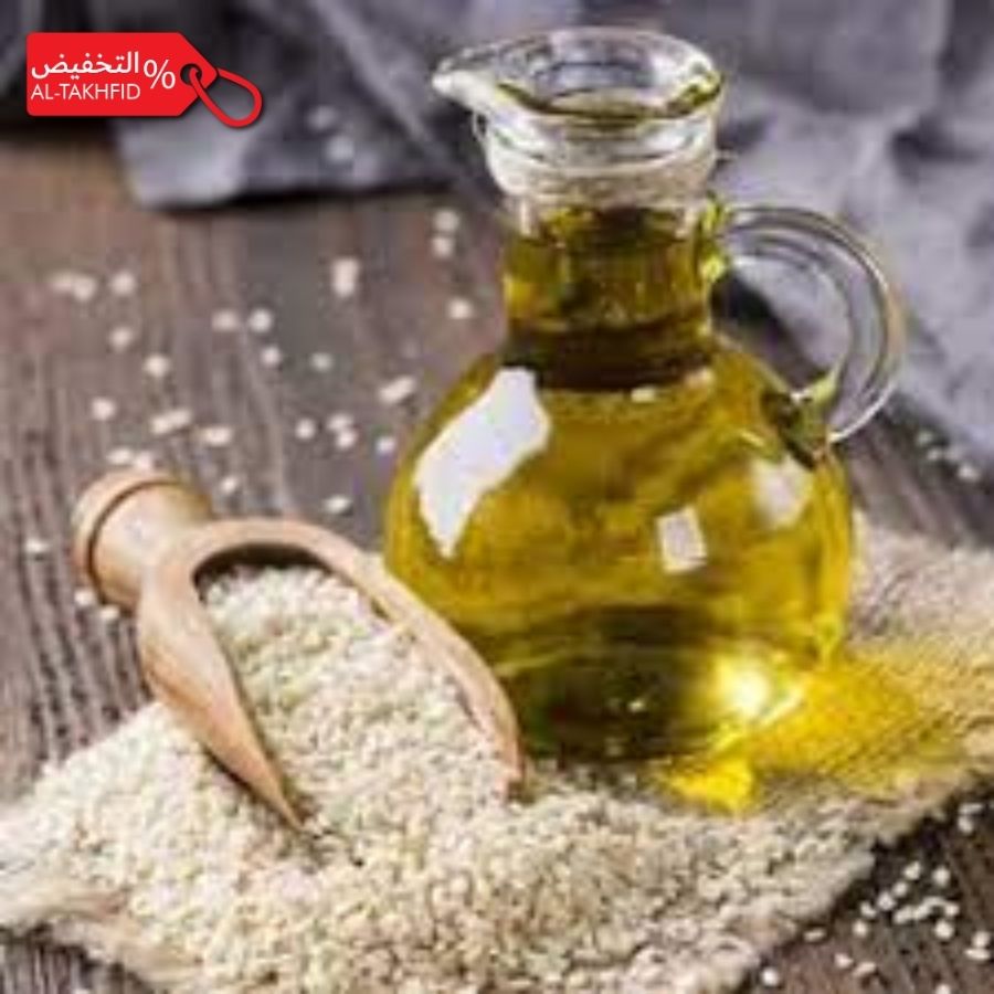Glass bottle of sesame oil with sesame seeds on a wooden surface, featuring promotional text.